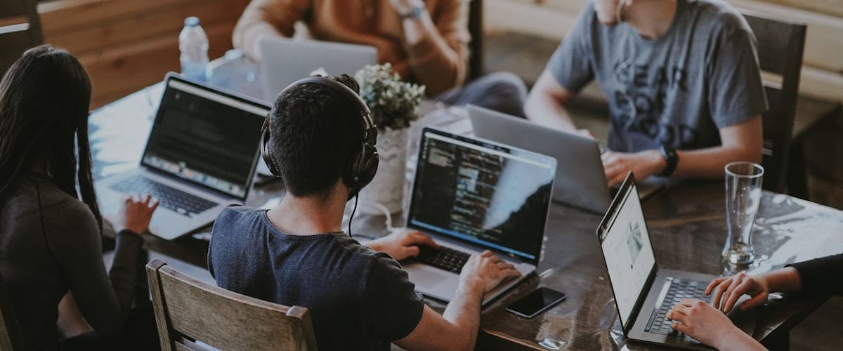 Mały zespół firmy pracujący razem przy laptopach — właśnie taki scenariusz dobrze obsługuje prosta aplikacja webowa
