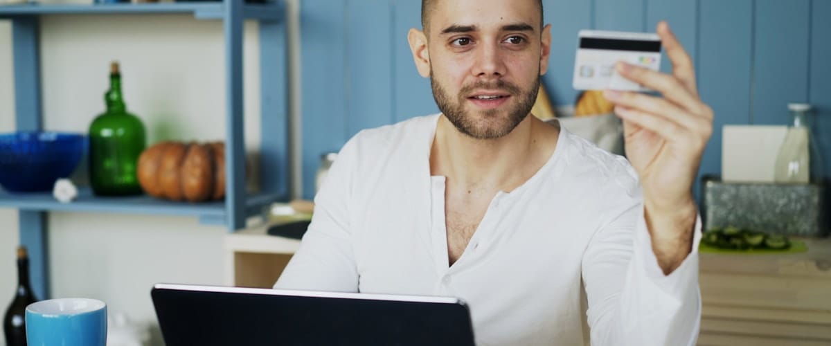 Mężczyzna z kartą kredytową przy laptopie — zakupy online w małym sklepie internetowym na WooCommerce